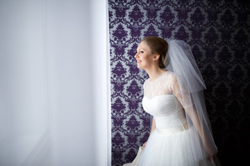 nice and gentle bride in a white dress standing at home