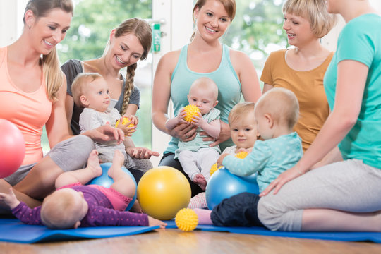 Junge Frauen in Mutter-Kind-Gymnastik spielen mit ihren Babys