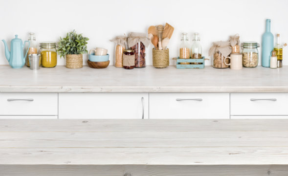 Wooden table over blurred kitchen furniture shelf with food ingredients
