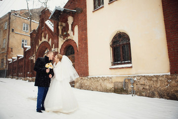 Beautiful bride and groom standing on a snowy street