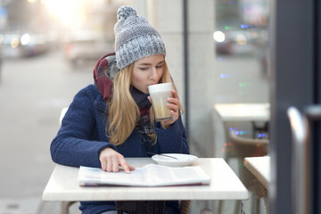 Junge Frau mit Kaffee und Zeitung