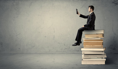 Man with laptop sitting on books