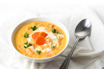 Carrot cream soup with parsley garnish and a spoon on a white napkin