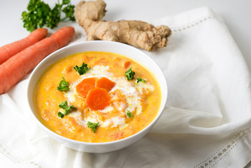 Carrot soup with ginger root and parsley garnish, white napkin