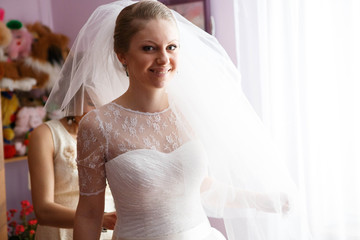 friend helping bride put on and lace up corset