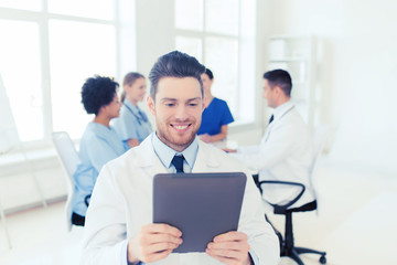 happy doctor with tablet pc over team at clinic