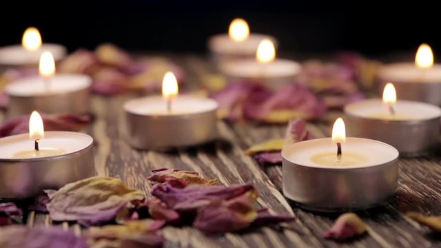 Lighted small candles and dried flowers roses on a wooden table