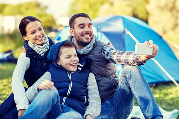 family with smartphone taking selfie at campsite