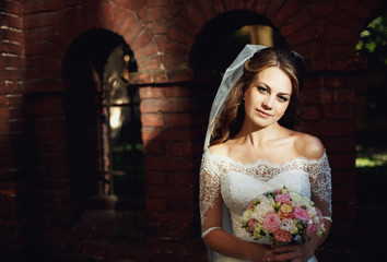 Happy beautiful bride posing on the old street