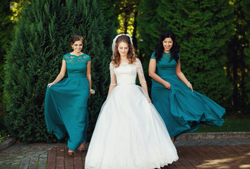Obraz na płótnie Canvas Happy beautiful bride with bridesmaids posing outside
