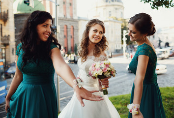 Naklejka premium Happy beautiful bride with bridesmaids posing outside