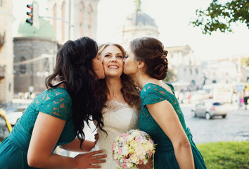 Happy beautiful bride with bridesmaids posing outside