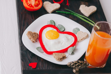 valentine day.romantic breakfast. fried egg, bread and vegetables on wooden tray 