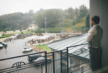 Groom in the classic outfit on the balcony