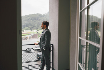 Serious groom is waiting on the hotel's balcony