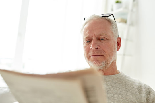 close up of senior man reading newspaper at home