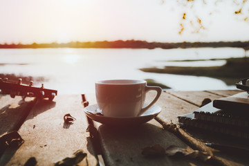 coffee on wooden floor with lake view background at sunset time.