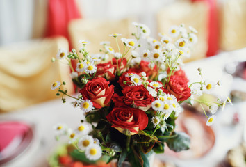 Red roses and chamomile on the wedding table