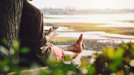 Man using mobile smart phone while relaxing on wooden balcony