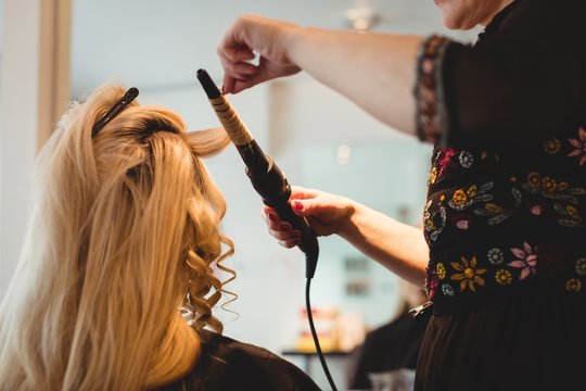 Female hairdresser styling clients hair in salon