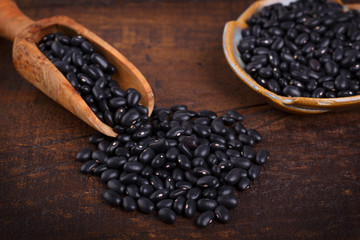 Black beans in scoop on wooden background