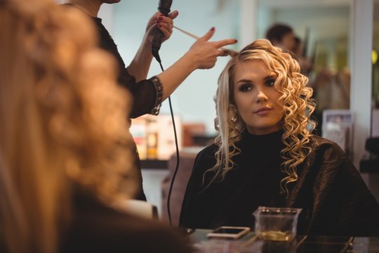 Female hairdresser styling clients hair