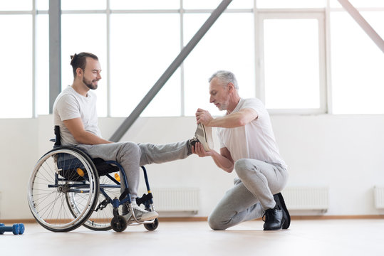 Aged orthopedist working with disabled patient in the gym