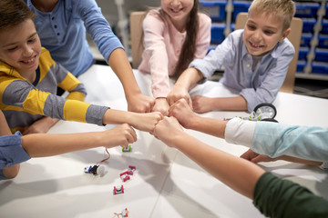 happy children making fist bump at robotics school
