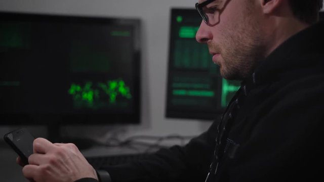 Close up of hacker using his gadget to match password and gain unauthorized access to data. Male spy hacking computer system with the help of smartphone downloading important data file from network.