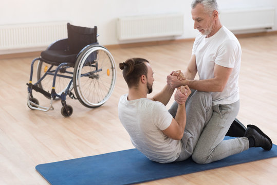 Skilled orthopedist assisting the disabled in the gym