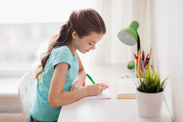 happy girl with book writing to notebook at home