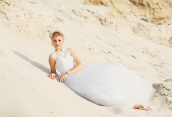 Pretty bride is lying on the white sand
