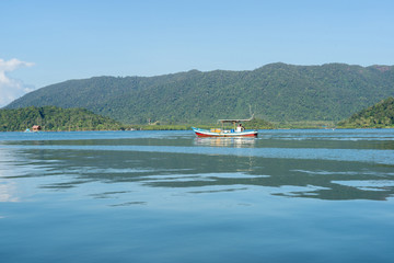 Small wooden boat on water with mountain background