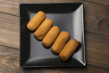 Tasty croquettes on black plate. Horizontal shoot.