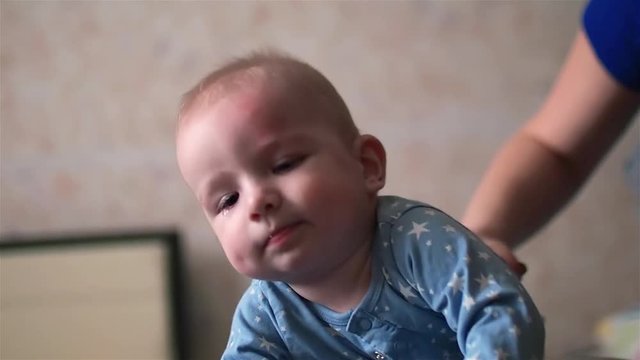 Little cute baby boy in star pyjamas doing gymnastics on fitball
