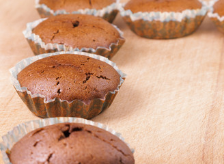 Muffin. Fresh baked cakes in paper baking dish with cracked surface on scratched wooden board.