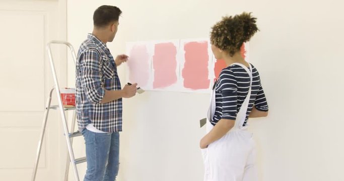 Young couple debating a new paint color for the wall of their home as they embark on a renovation project