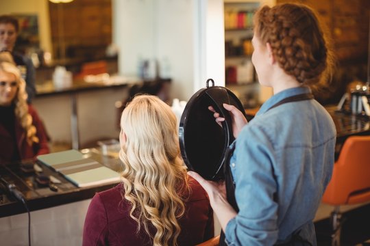 Female hairdresser showing the haircut of client in mirror 