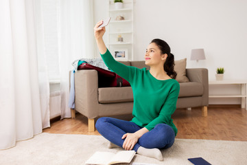 woman with smartphone taking selfie at home