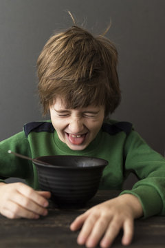 Boy grimacing at a bowl of food