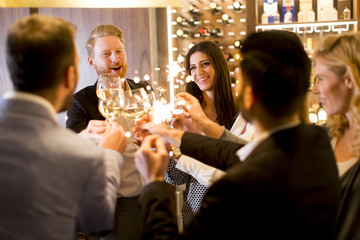 Group of young people celebrating and toasting with white wine