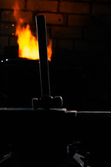 Blacksmith hammer on the anvil against the background of fire.