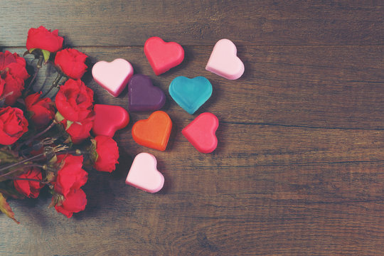 Valentine's day concept :Colorful heart-shaped soaps and roses on wood background
