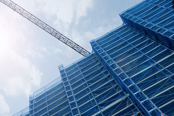 Obraz premium A crane in a construction work. Tall scaffold structure from below. Empty copy space for Editor's text.