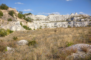 View on hills and fields from a limestone cliff at a quarry under a beautiful blue sky, abandoned white stone career, in fetesti village, Moldova