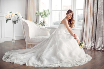 Bride in beautiful dress sitting resting on sofa indoors
