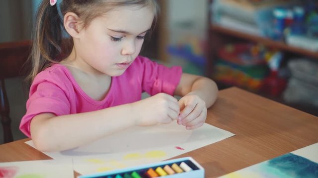 Girl draws with crayons at the table