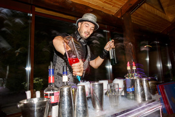 Bartender with bottles with alcoholic drinks on cocktail party