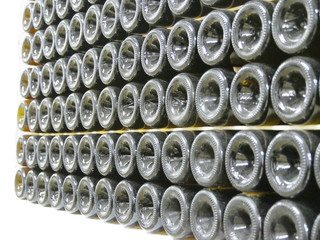 Old bottles of wine in rows in wine cellar. Rows of many wine bottles in winery cellar storage....