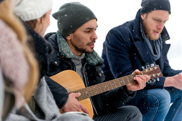 Young people playing guitar on winter day